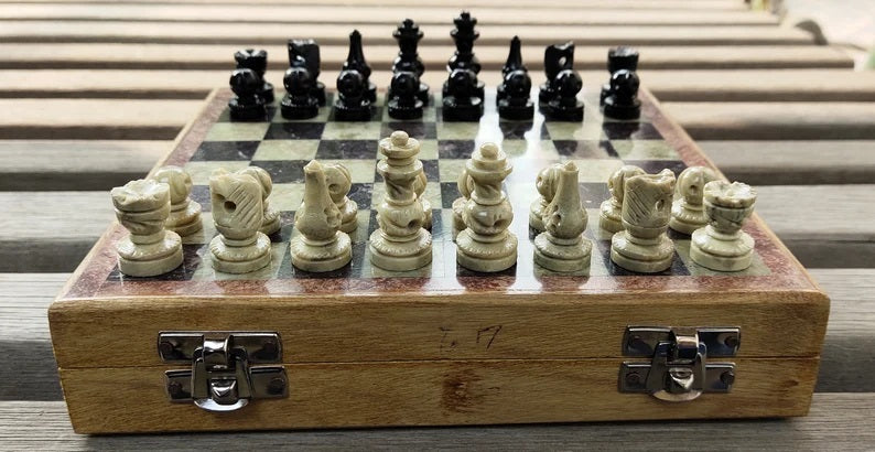 Chess set with pieces on a wooden board, placed on a wooden surface.