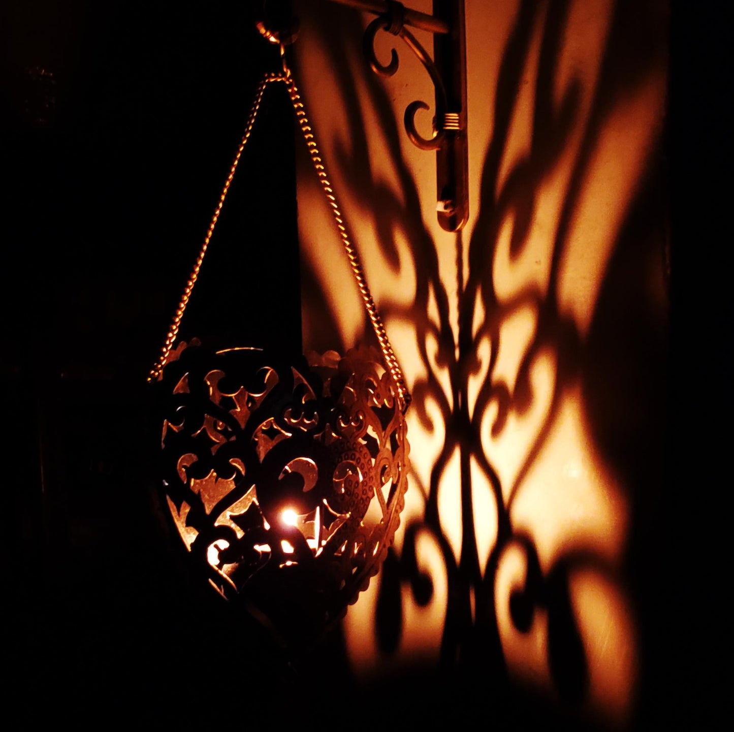 Decorative lantern casting shadows on a wall with a warm glow.