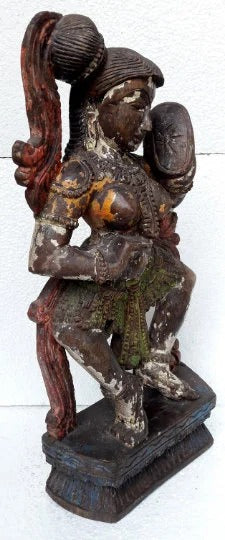 Wooden sculpture of a figure with long hair and traditional attire on a white background
