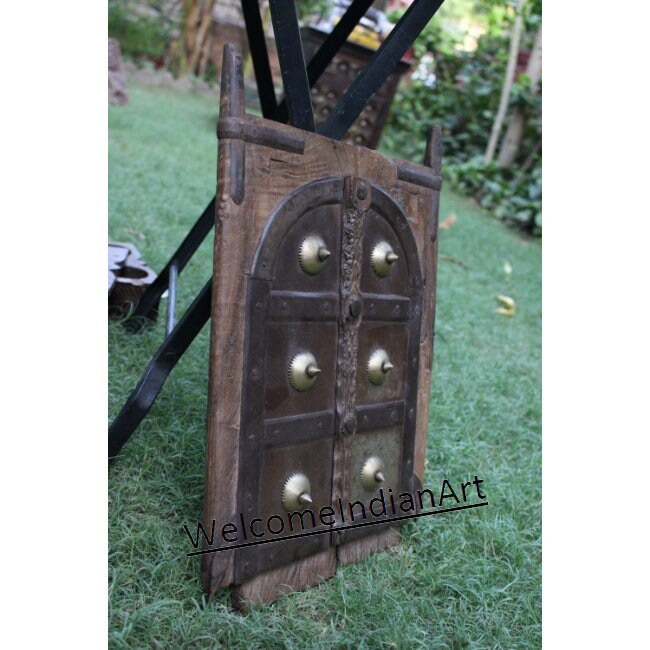 Decorative wooden door with brass knobs on a grassy background, branded 'Welcome Indian Art'.