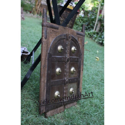 Decorative wooden door with brass knobs on a grassy background, branded 'Welcome Indian Art'.