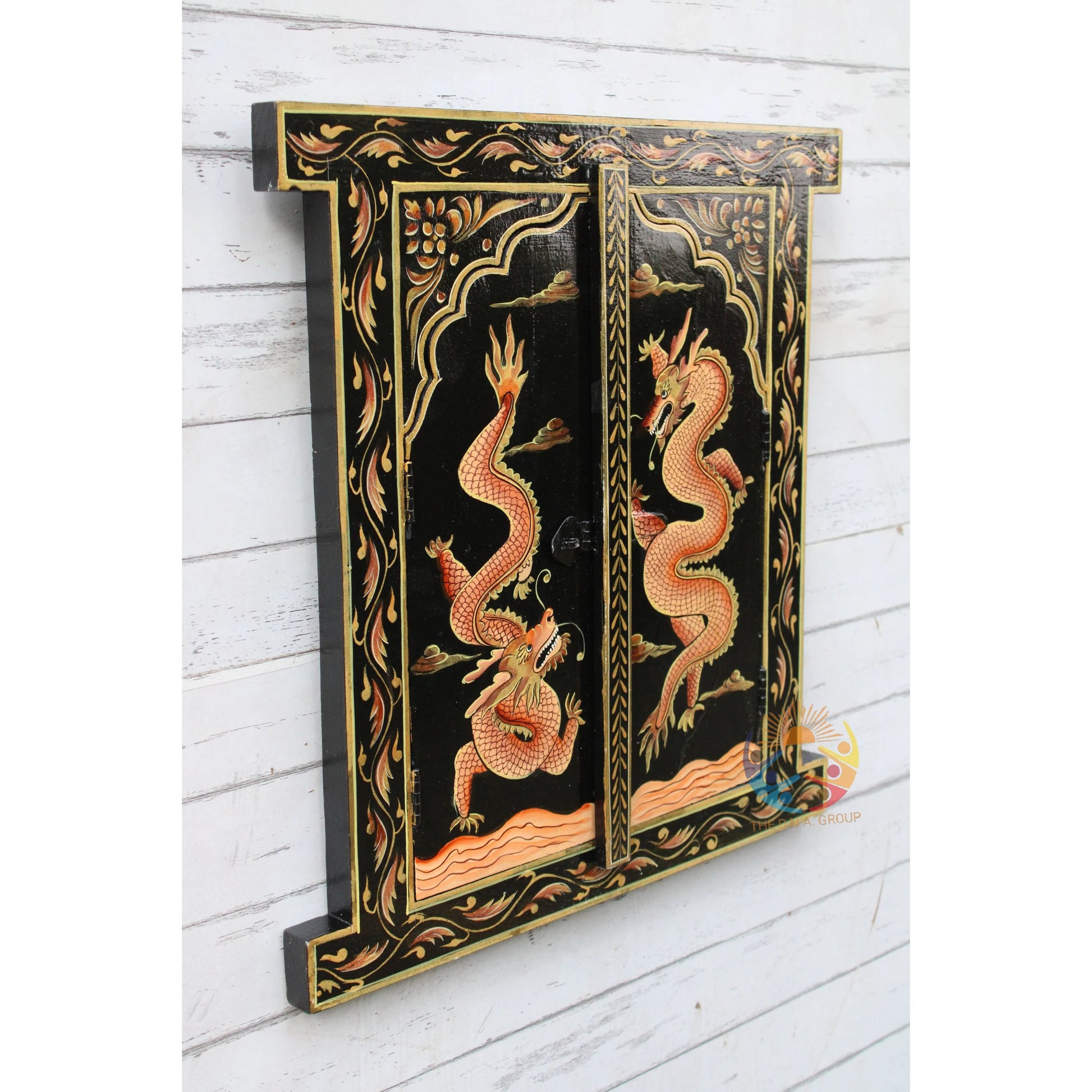 Decorative panel with dragon design on a black background, mounted on a white wooden wall.