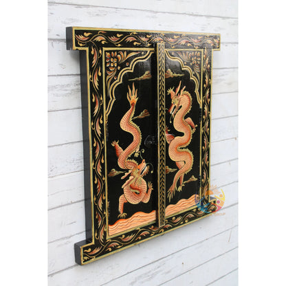 Decorative panel with dragon design on a black background, mounted on a white wooden wall.