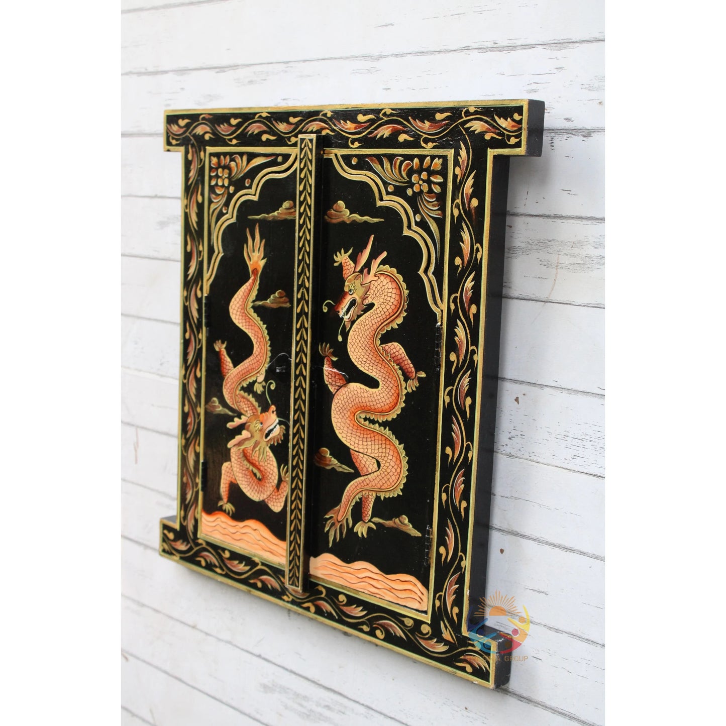 Decorative panel with dragon design on a black background, mounted on a white wooden wall.