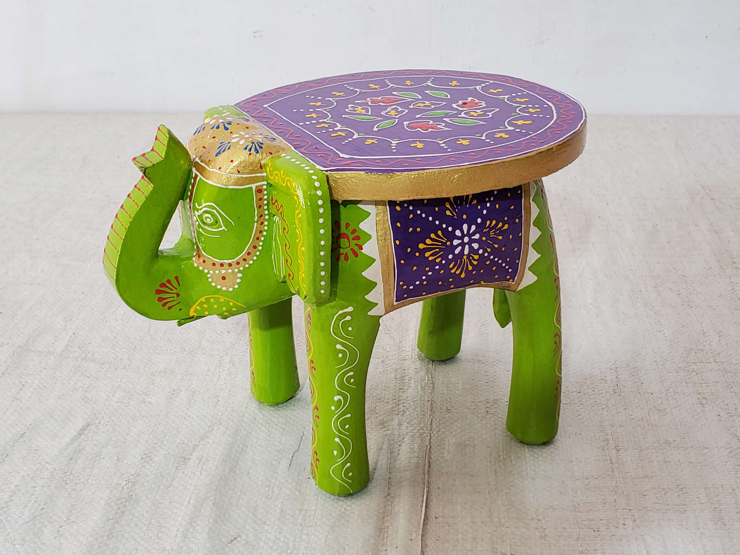 Decorative stool shaped like an elephant with a purple top on a light background