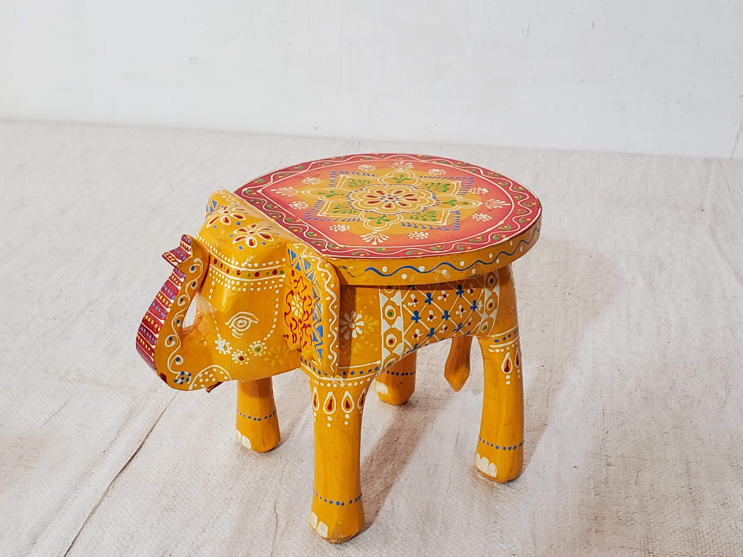 Decorative stool shaped like an elephant with colorful patterns on a white background