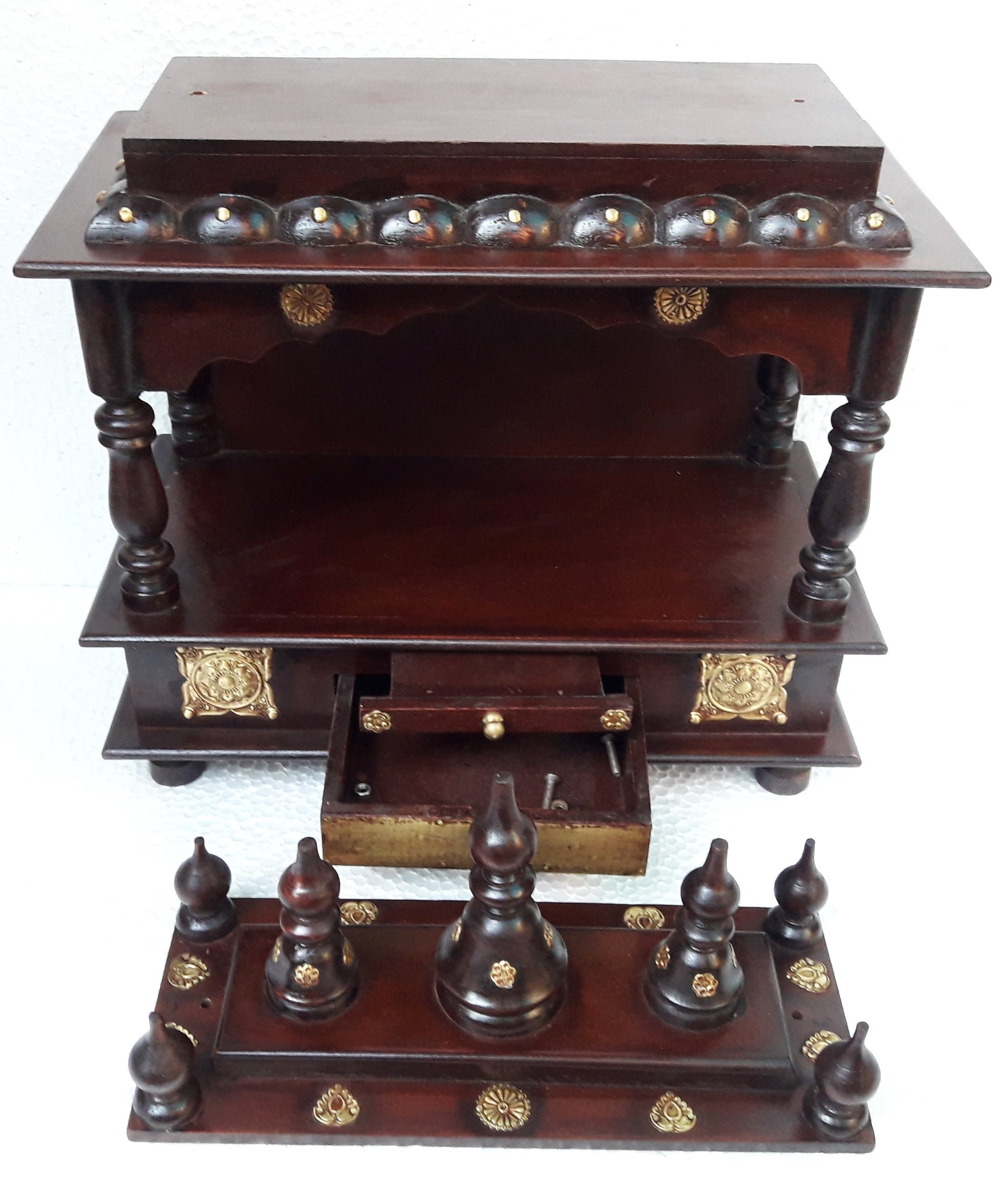 The INDIAN CRAFTS STORE Handcrafted Wooden Pooja Ghar Art Wooden features intricate carvings, ornate pillars, golden accents, a decorative top shelf, pull-out drawer, and detachable spire-adorned base—ideal for home decor or gifting.